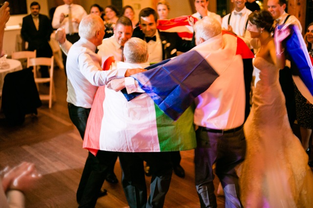 a group of italian french and american wedding attendees dance with their native flags in celebration of their families uniting
